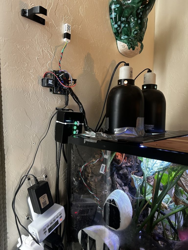 This image shows a terrarium sensor active monitoring system with circuit boards, screens, and plants inside an enclosure